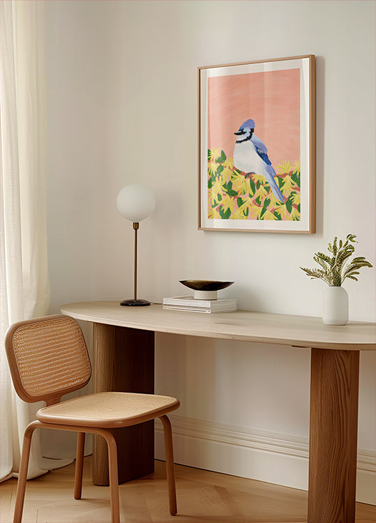 um canto aconchegante de uma sala com uma mesa de madeira, uma cadeira de tecido, uma luminária e uma foto emoldurada de um pássaro azul sobre fundo amarelo.