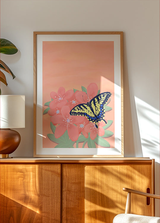 uma pintura emoldurada de uma borboleta em uma flor rosa, exibida em um armário ou prateleira de madeira.