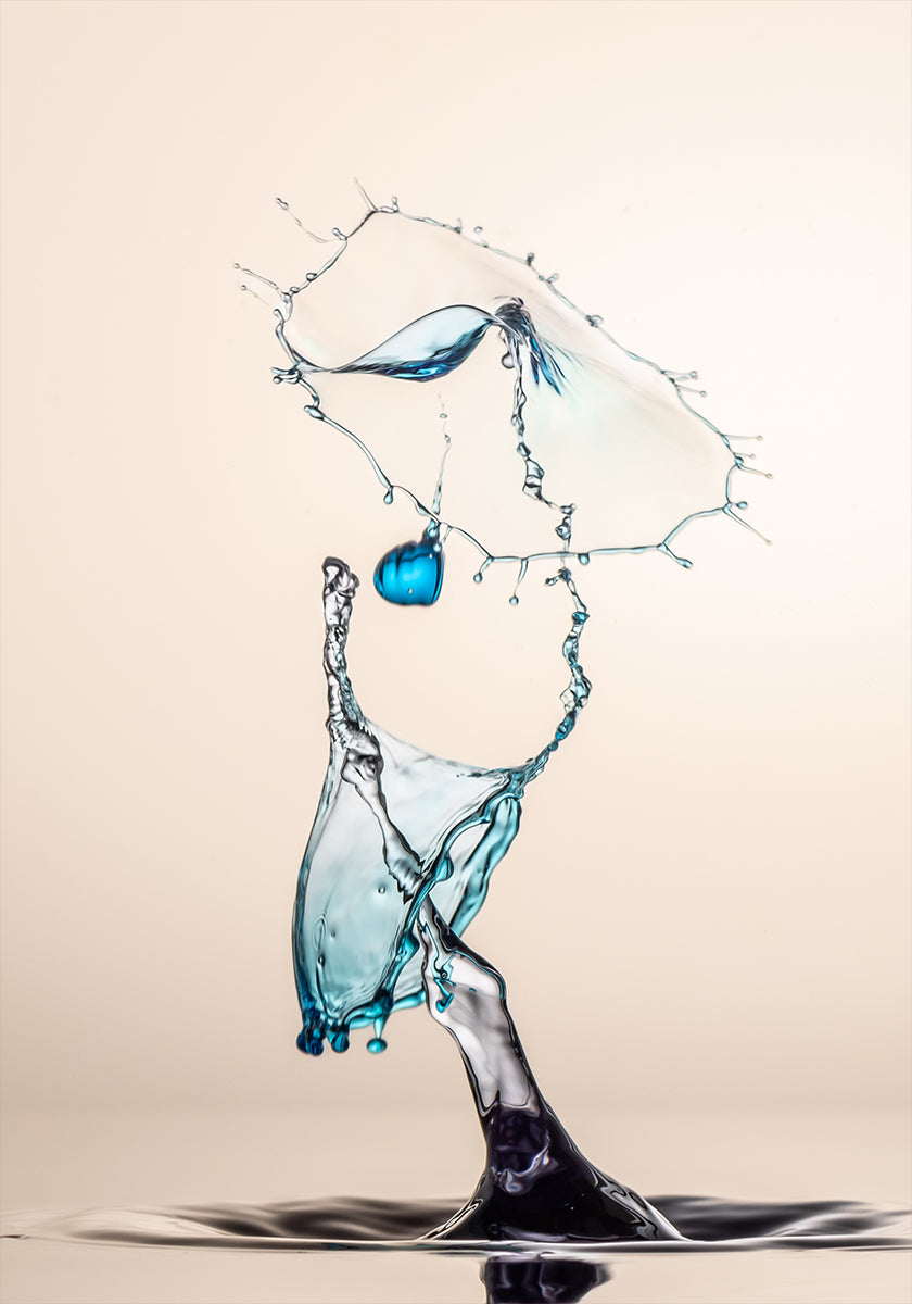 um respingo de água dinâmico, com um objeto azul suspenso no ar e um grande respingo de água caindo em cascata, criando uma sensação de movimento e energia.