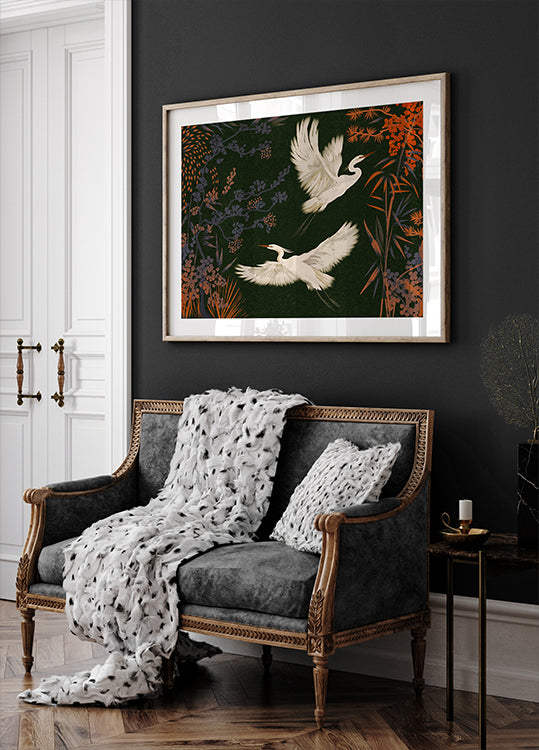 um sofá preto e branco com uma manta branca e duas almofadas brancas, encostado em uma parede escura com uma pintura emoldurada de dois pássaros brancos voando acima dela.