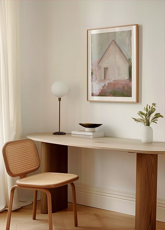 um espaço de trabalho moderno e minimalista com uma mesa de madeira, uma cadeira de tecido, uma luminária e uma pintura emoldurada de uma casa.