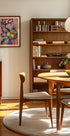 uma sala aconchegante e bem organizada com estante de madeira, mesa redonda de madeira e cadeira de madeira. A sala tem um ambiente acolhedor e convidativo, com um quadro na parede e uma fruteira sobre a mesa.